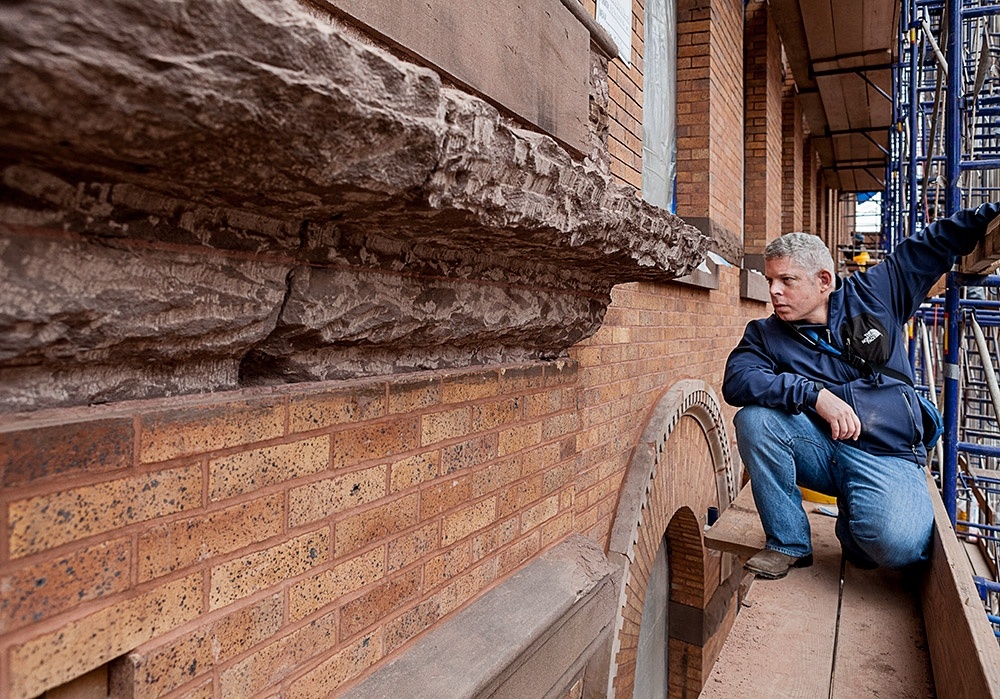 a man sitting on a ledge next to a building