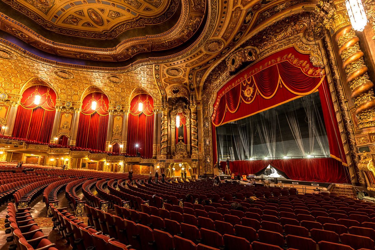 an empty theatre with red curtains and gold trim