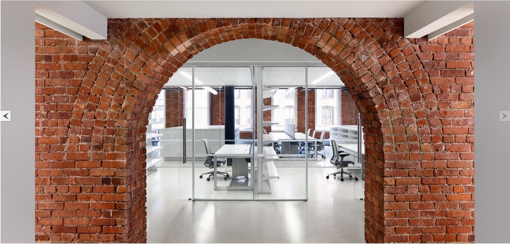 an office with a brick archway and glass walls