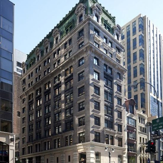 a tall building with a green roof on the corner of a street