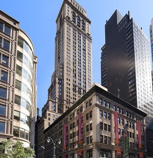 a yellow car driving down a street next to tall buildings