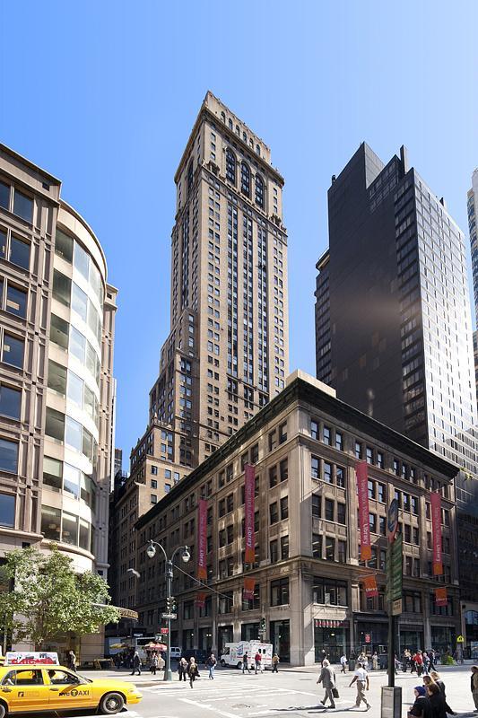 a yellow car driving down a street next to tall buildings