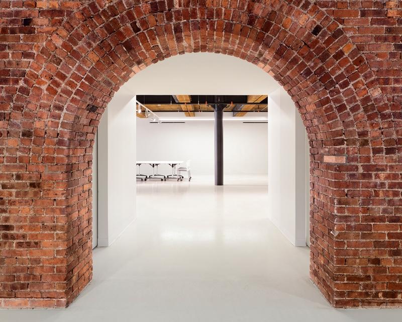 an empty room with a brick archway leading to a meeting room