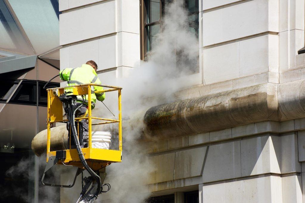 a man on a lift working on a pipe