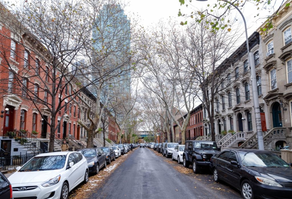 a street lined with parked cars next to tall buildings