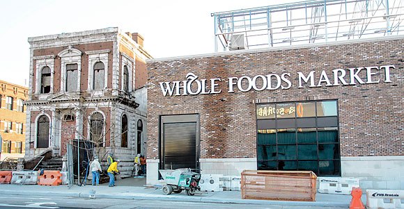 people are walking past a whole foods market