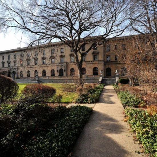 a large building with trees and bushes in front of it