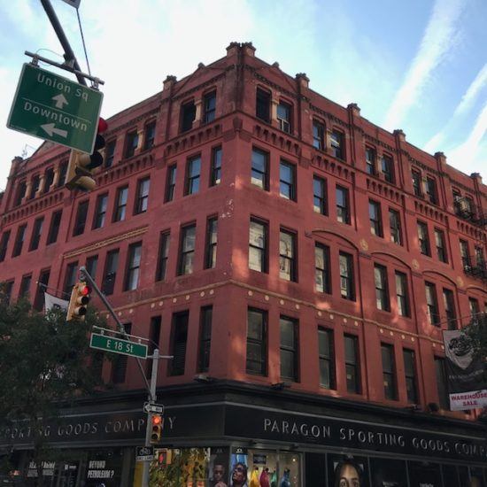 a red brick building with many windows and street signs