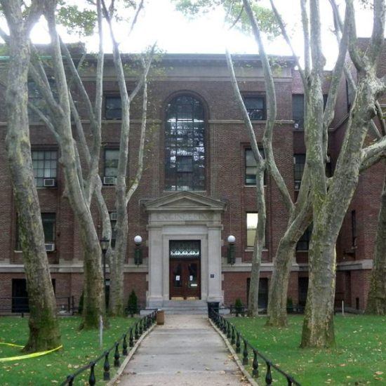 a brick building with many trees in front of it