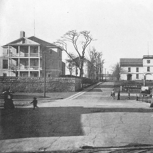 an old black and white photo of people walking down the street