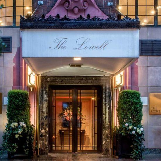 the front entrance of a hotel with flowers and potted plants