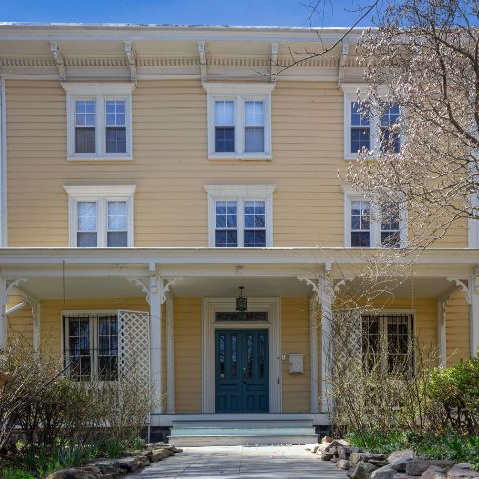 a large yellow house with two stories and a blue door