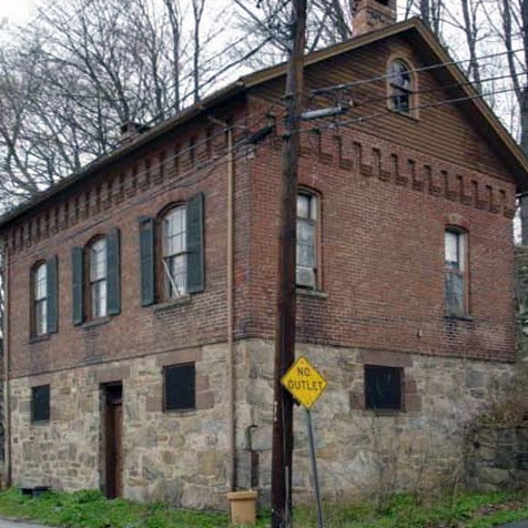 an old brick building sitting on the side of a road