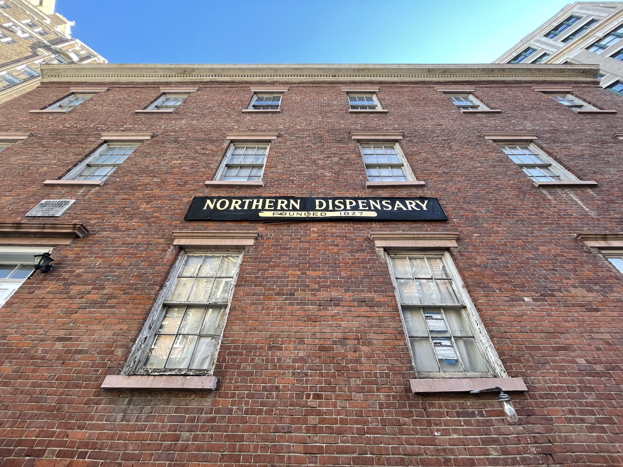 a tall brick building with windows and a sign on it