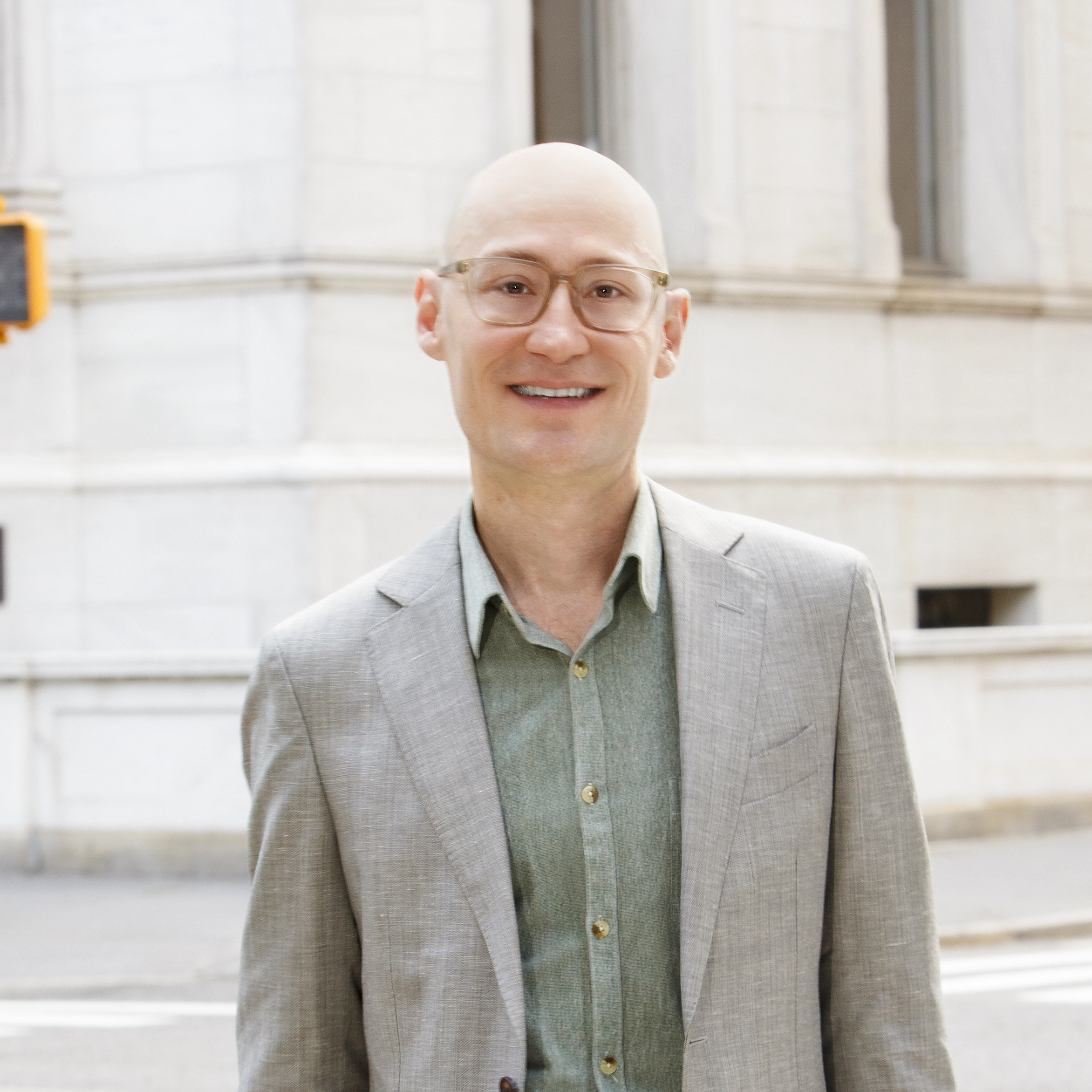 a man in a suit and glasses standing on the street