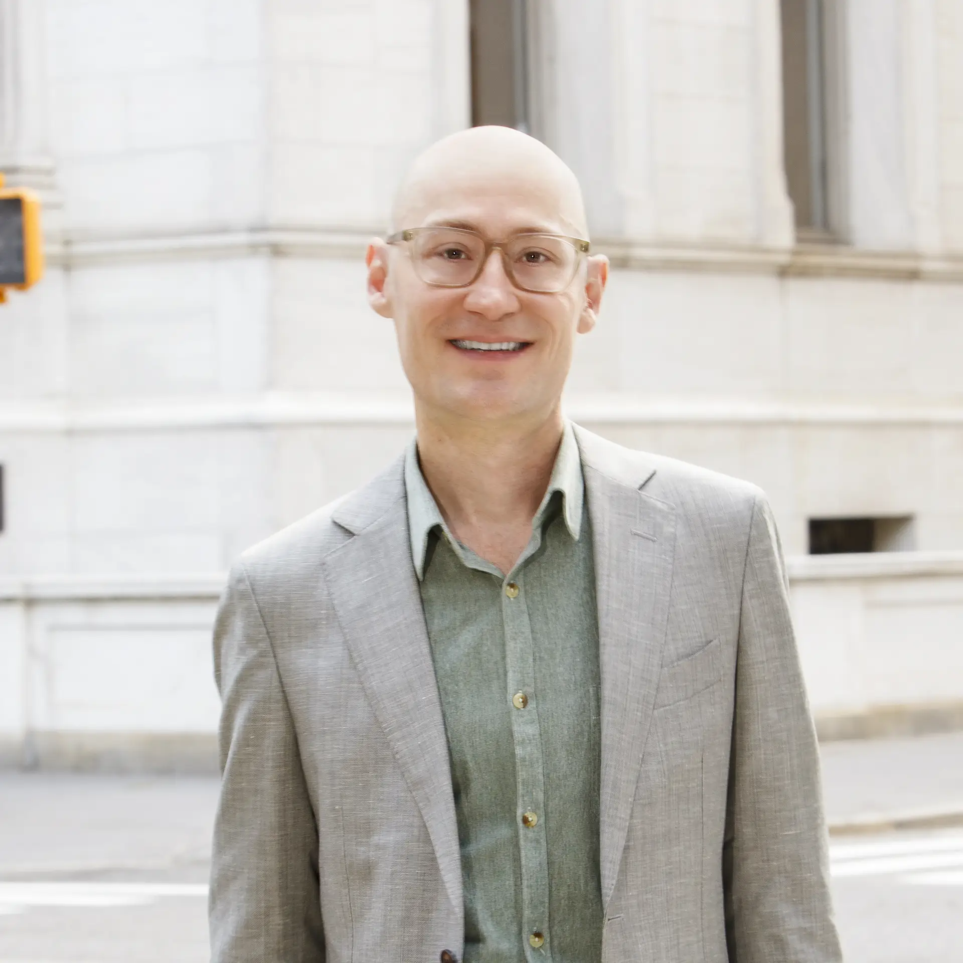 a man in a suit and glasses standing on the street