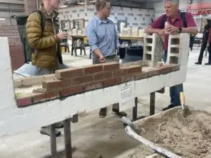 two men are working on a brick wall