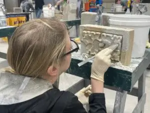a woman is working on a sculpture in a factory