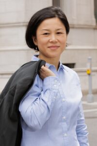 a woman in a blue shirt is holding a black jacket